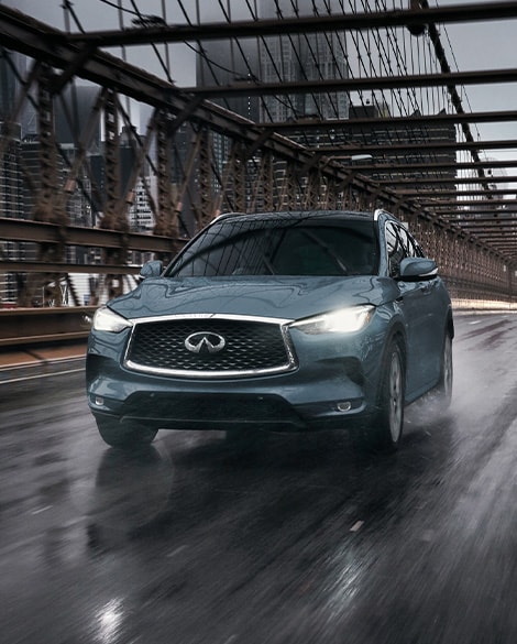 INFINITI QX50 driving in wet conditions on a bridge