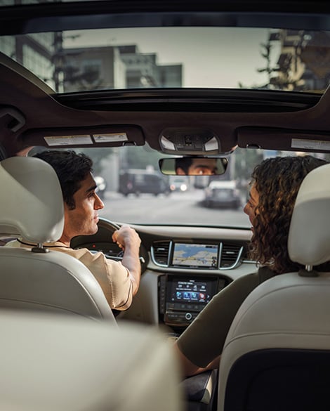 Man and woman talking to each other in the driver and passenger seat of an INFINITI crossover SUV