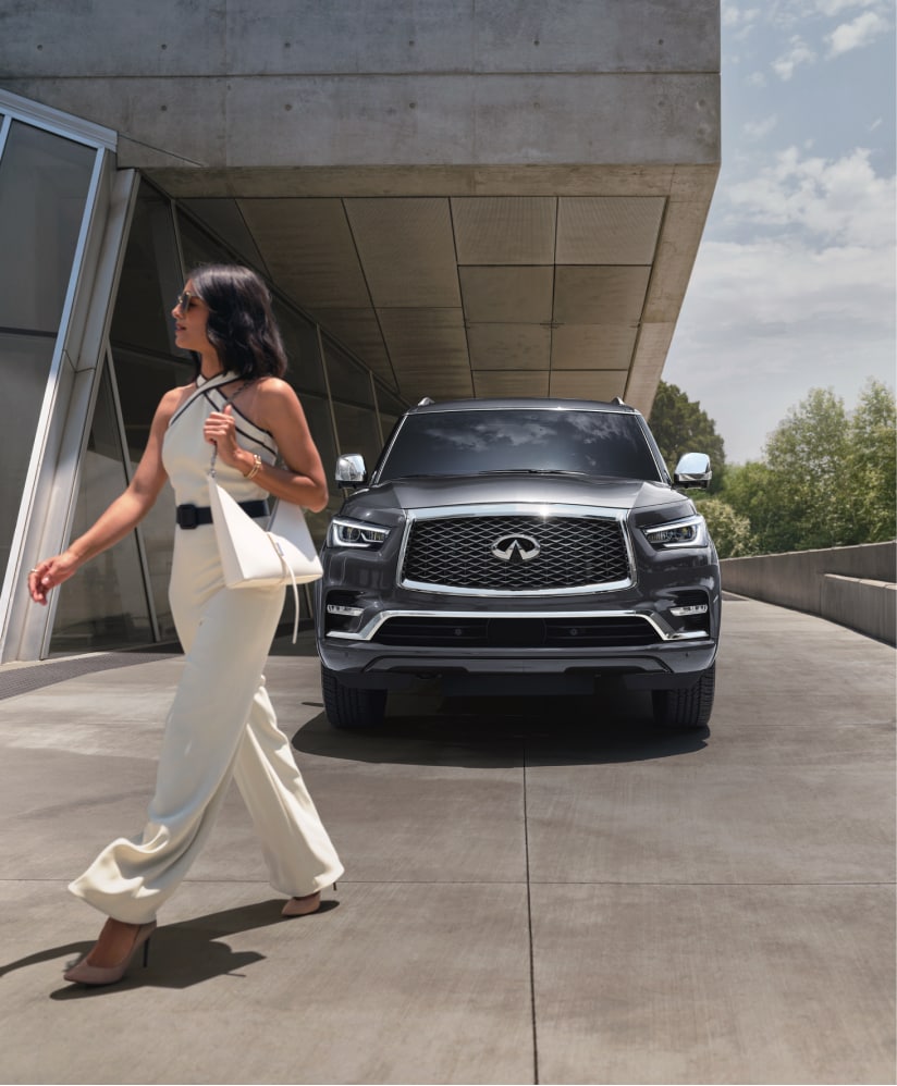 Woman walking in front of INFINITI QX80 parked for INFINITI Valet Service