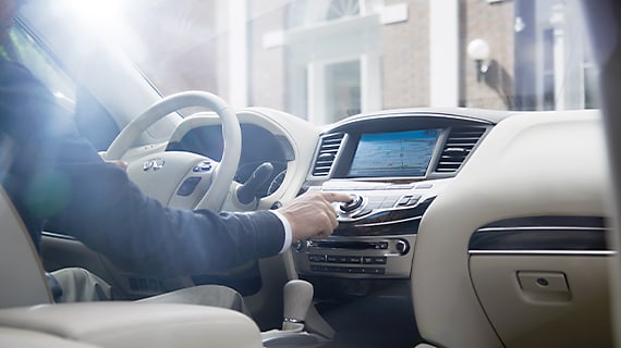 Interior view of man using the 2013 INFINITI JX35's infotainment system, highlighting interior technology features