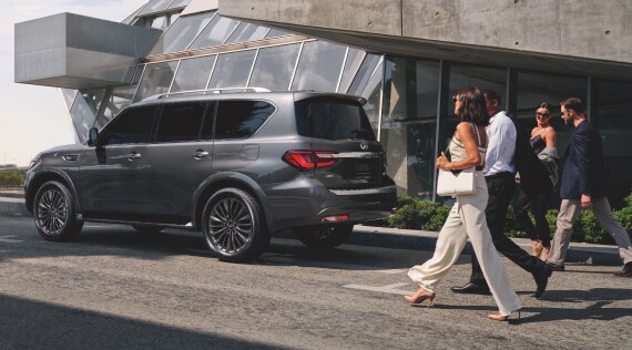 Couple walking behind an INFINITI QX80 Full-size luxury SUV