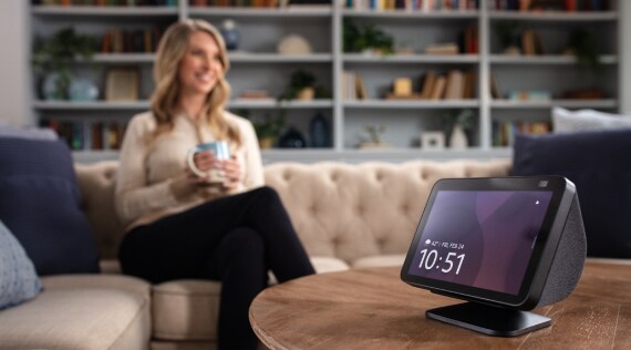 Woman sitting on couch with smart home screen showing time and date