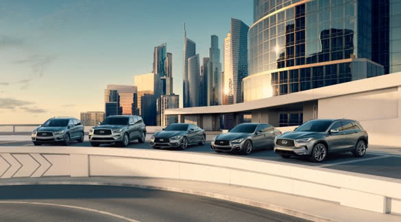 Image of INFINITI model lineup parked on an elevated platform positioned in front of downtown city landscape