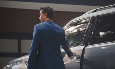 Image of a man in a suit entering the driver door of an INFINITI QX80 Luxury SUV
