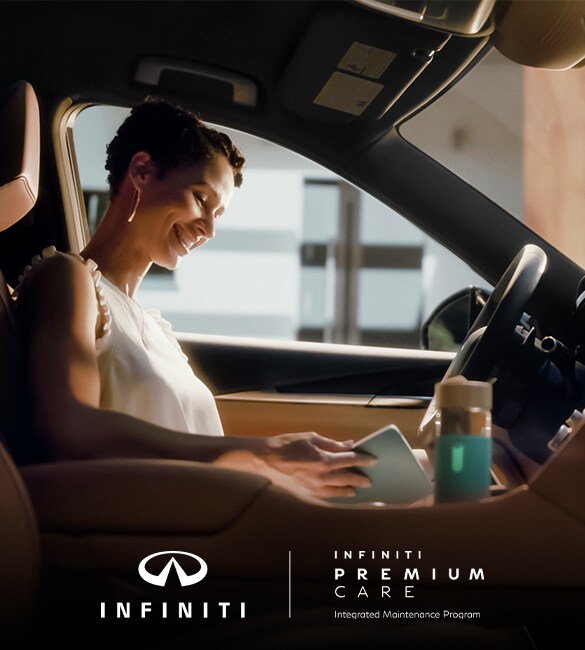 Woman sitting in driver seat of INFINITI QX60 reading her tablet