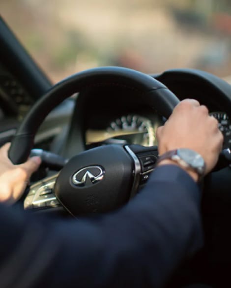 Interior view of a mans hands on a 2024 INFINITI Q50 steering wheel