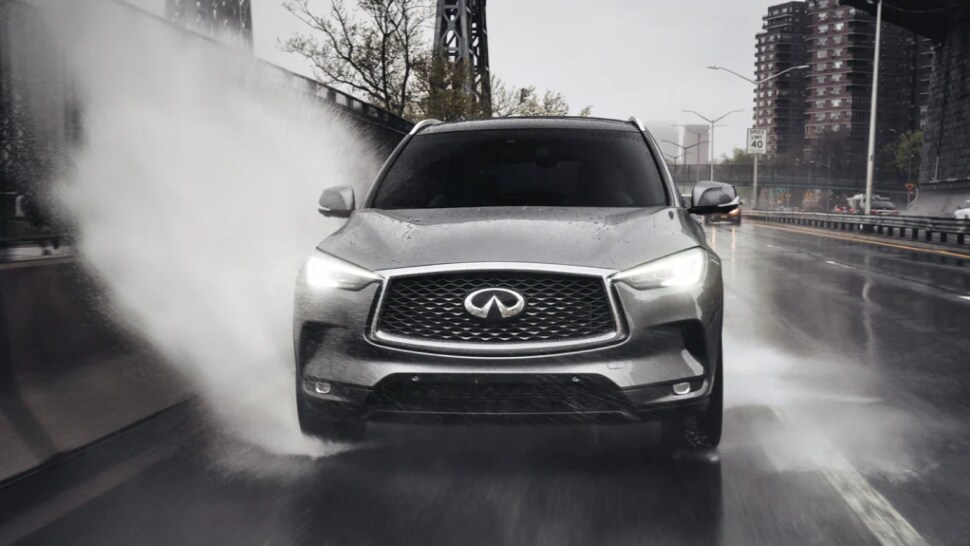 Front profile view of 2023 INFINITI QX50 driving through a puddle highlighting Intelligent AWD feature