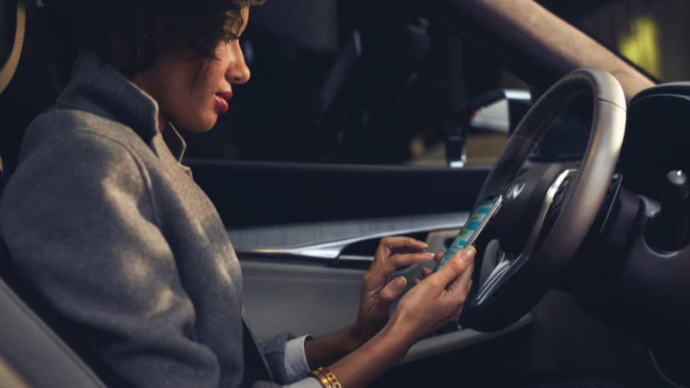 Interior of 2023 INFINITI QX50 featuring woman using QX50's connectivity features