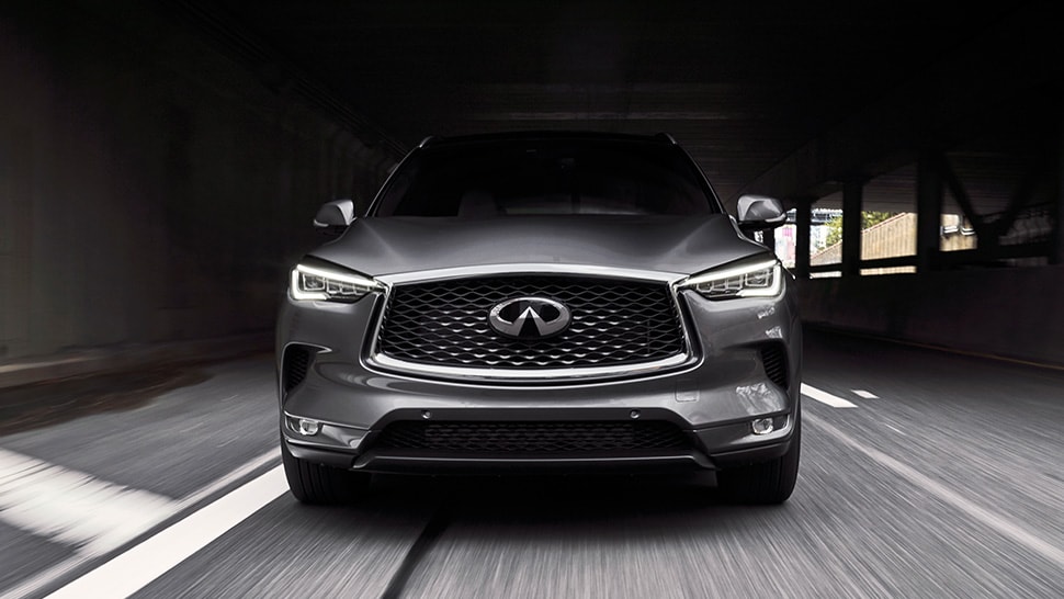 Front profile view of 2024 INFINITI QX50 driving through a puddle highlighting Intelligent AWD feature
