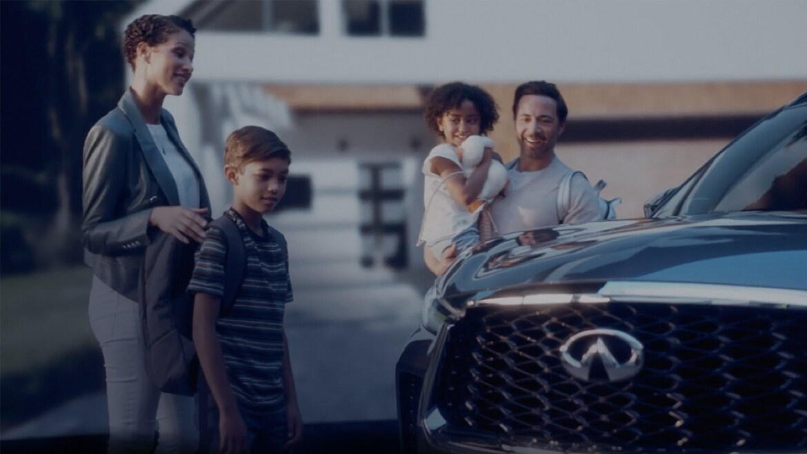 Family standing beside the 2022 INFINITI QX60 shown in Moonbow Blue color