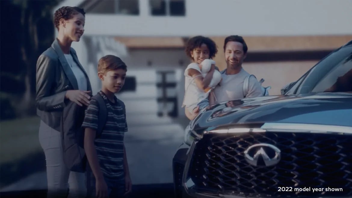 Family standing beside the 2023 INFINITI QX60 shown in Moonbow Blue color