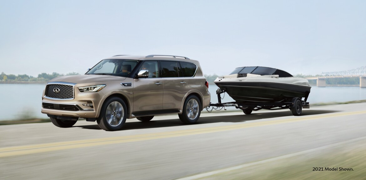 Side profile view of 2023 INFINITI QX80 towing a boat