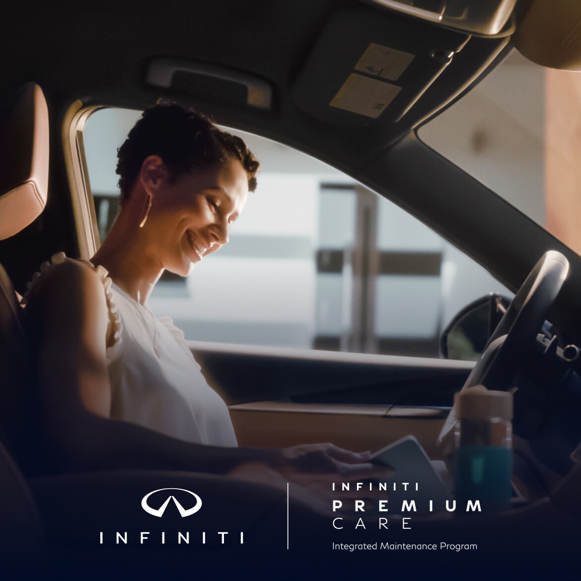 2024 INFINITI QX80 interior with woman smiling at her INFINITI Premium Care plan