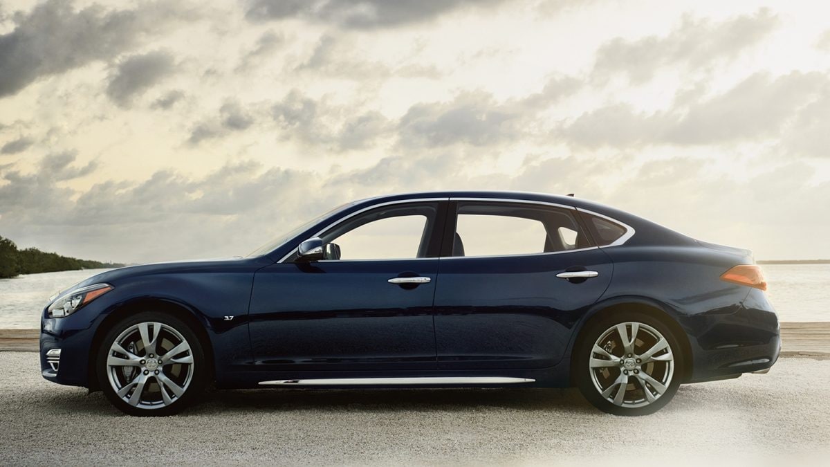 Driver Side Exterior View Of The 2019 INFINITI Q70L Luxury Sedan In Hermosa Blue And Chrome Trim Parked On Road