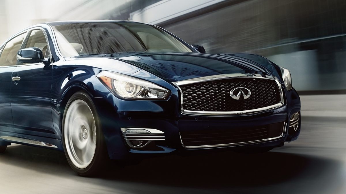 Exterior Front Profile View OF The 2019 INFINITI Q70L Sedan Driving Down Road Highlighting Headlights And Front Bumper