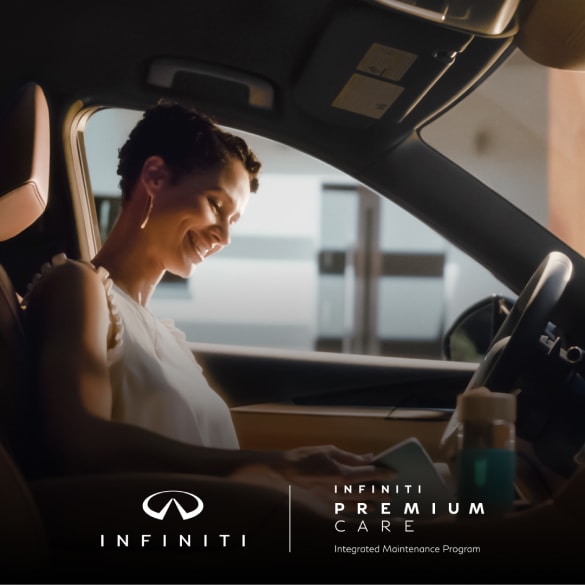 Woman sitting in driver seat of INFINITI QX60 reading her tablet